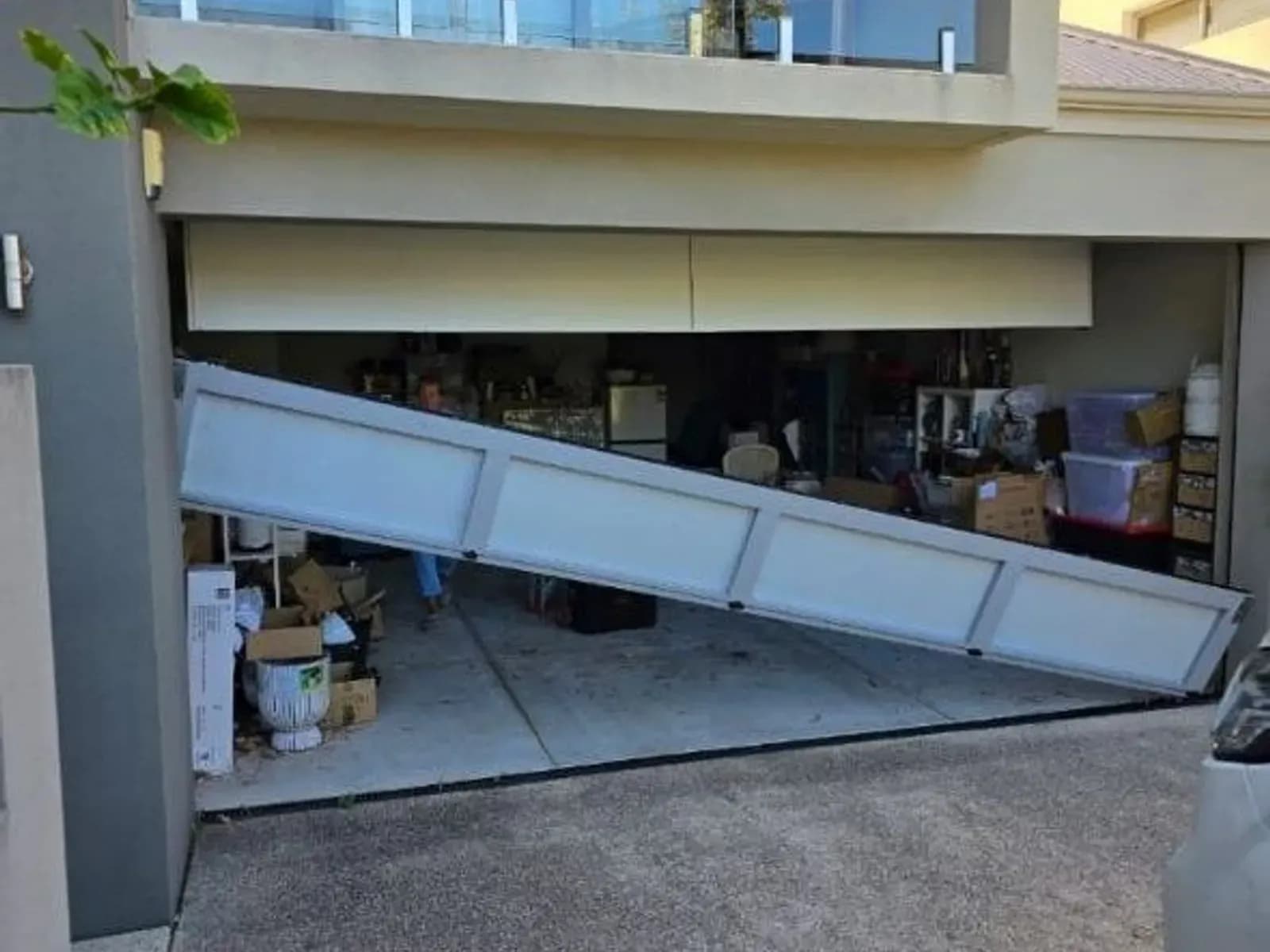 Sectional garage door collapsed diagonally out of its tracks across the opening of a two-storey Perth home