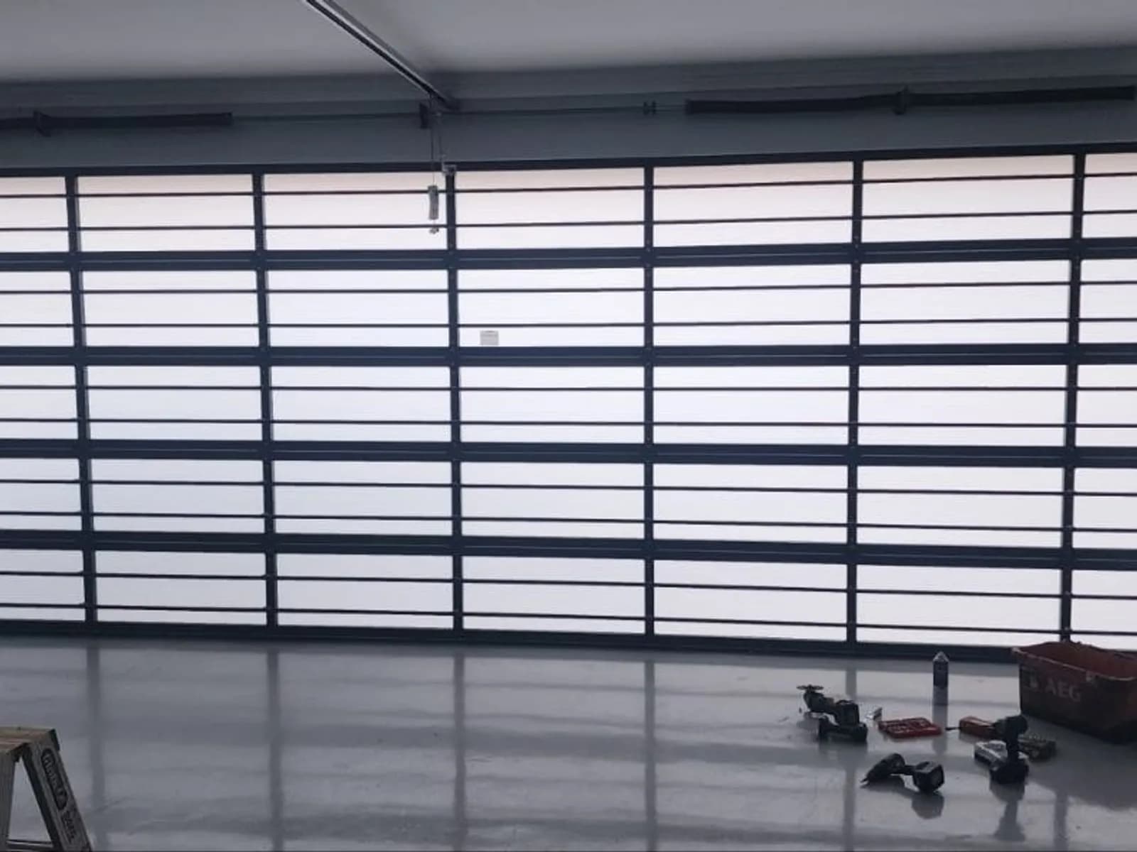 Aluminium-framed sectional garage door with glass panels fitted flush to the opening of a rendered garage