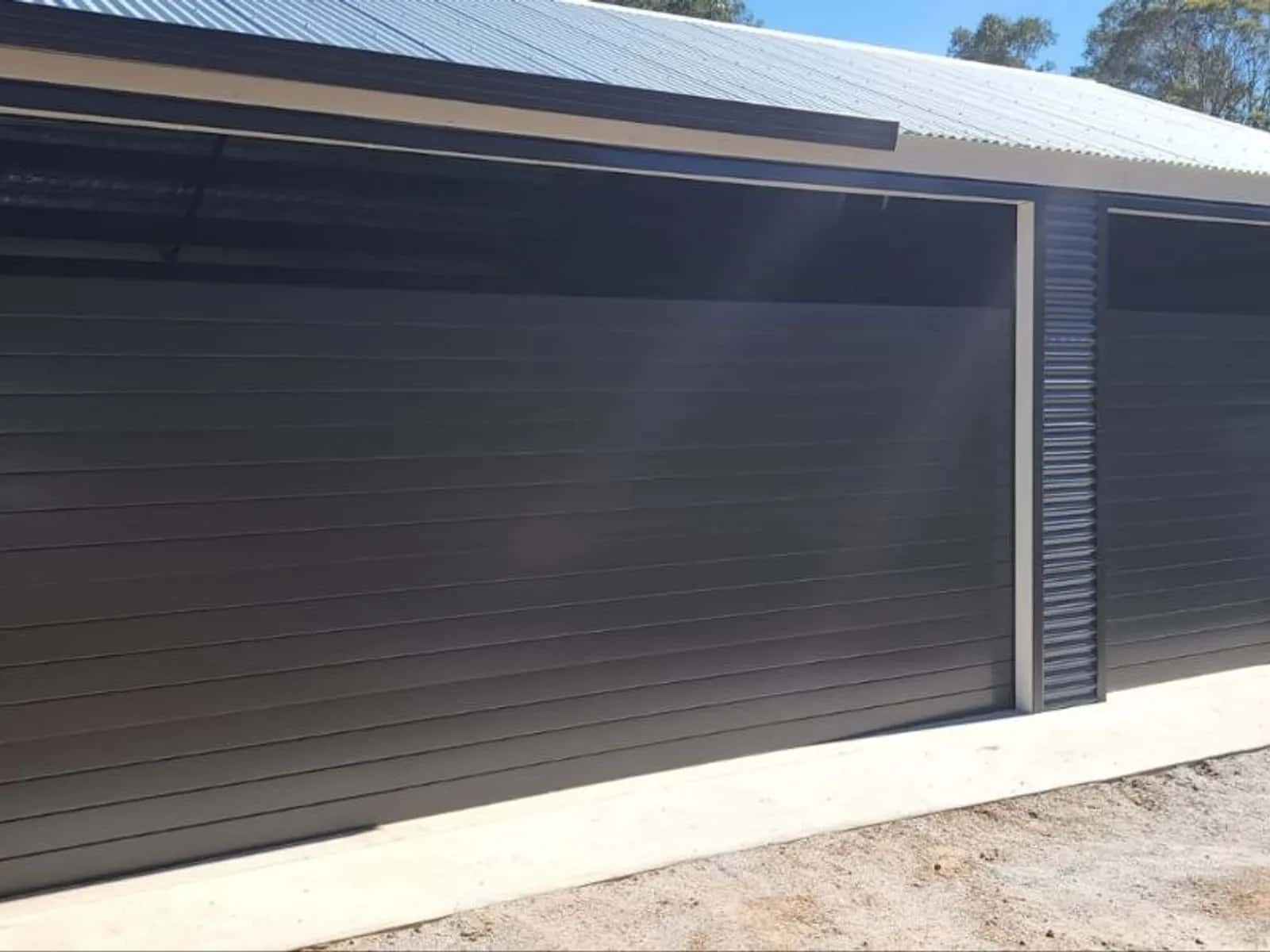 Two charcoal roller doors fitted side by side on a double shed