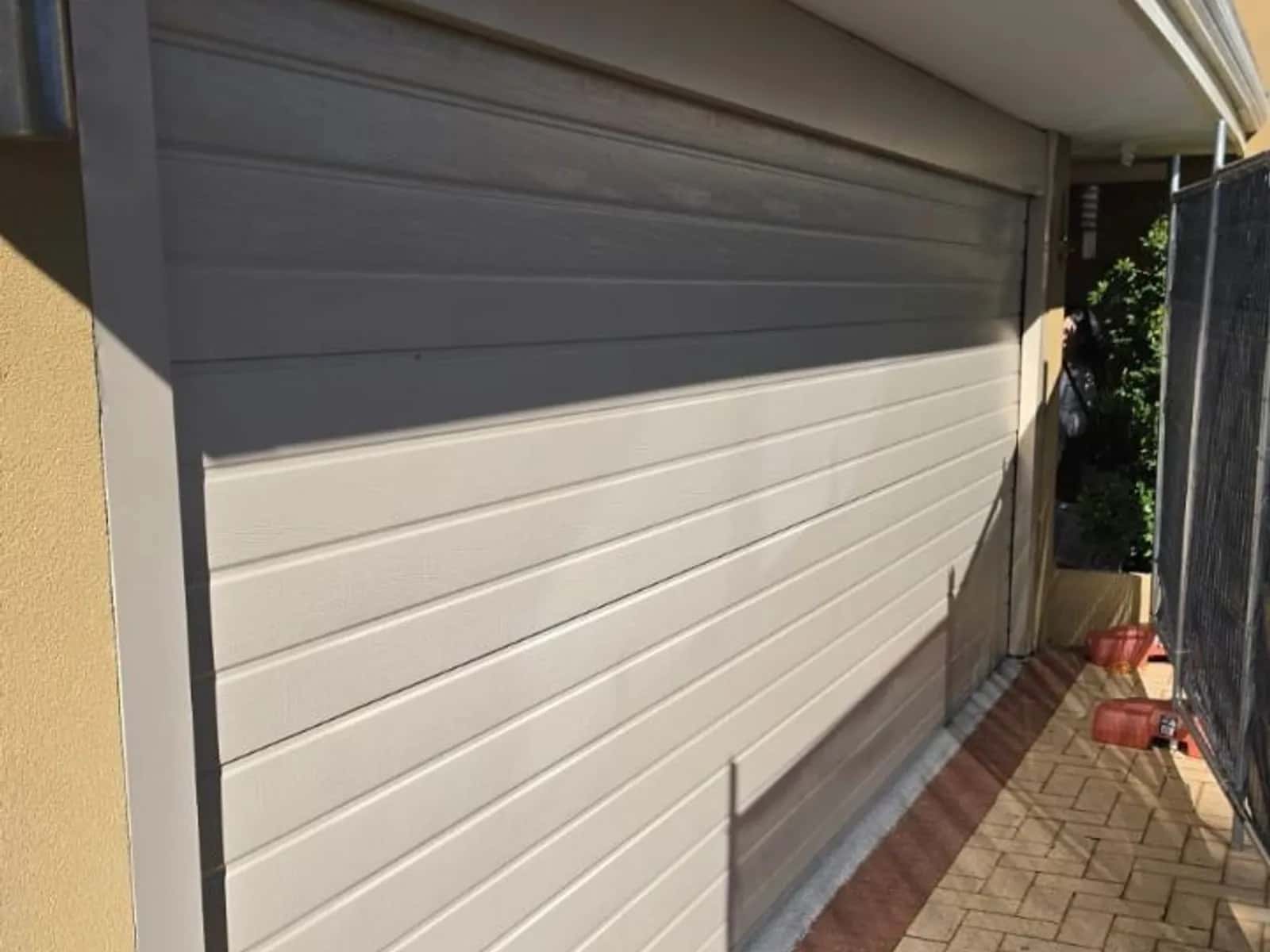 Cream sectional garage door viewed from the side with its panels closed