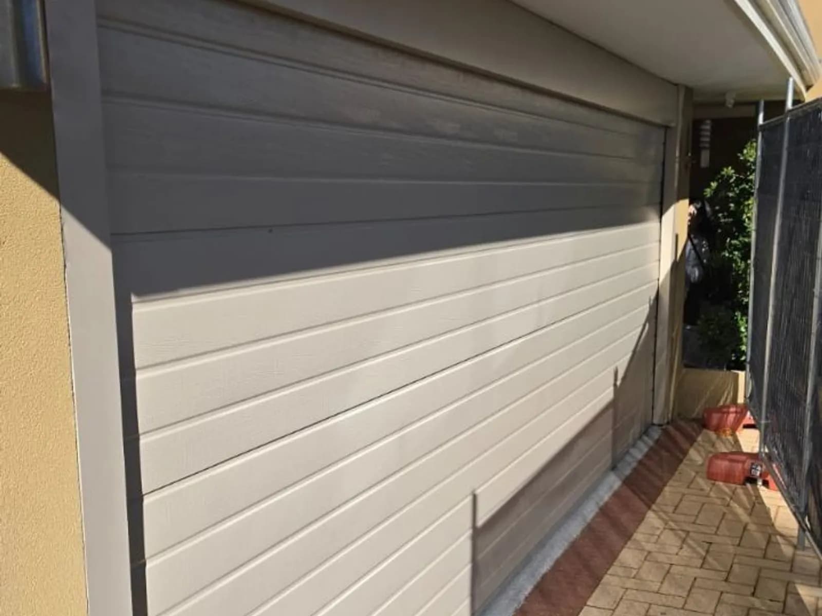 Cream sectional garage door viewed from the side with its panels closed Cream sectional garage door viewed from the side with its panels closed