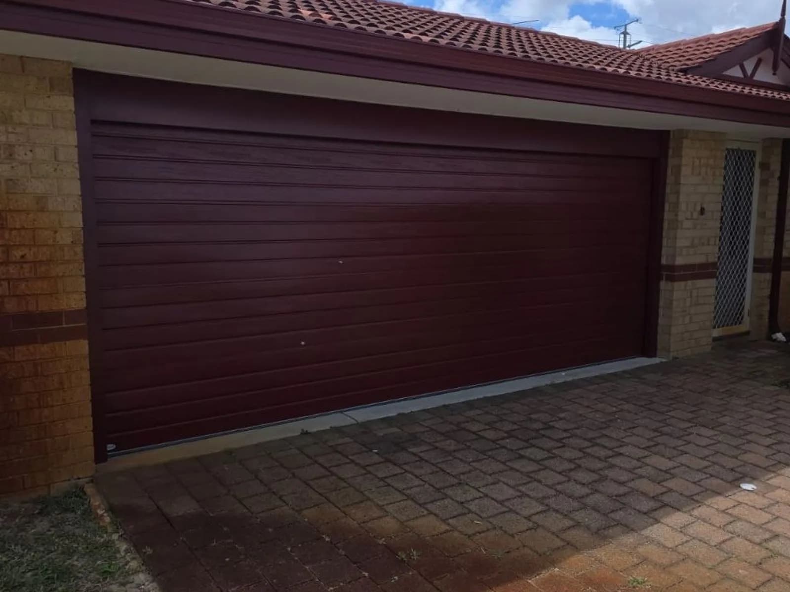 Maroon Colorbond roller door across a double garage Maroon Colorbond roller door across a double garage