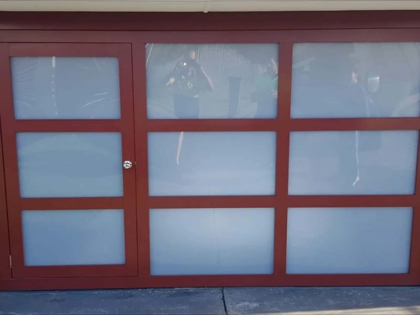 Red-framed sectional garage door with full-height glass panels on a Perth home