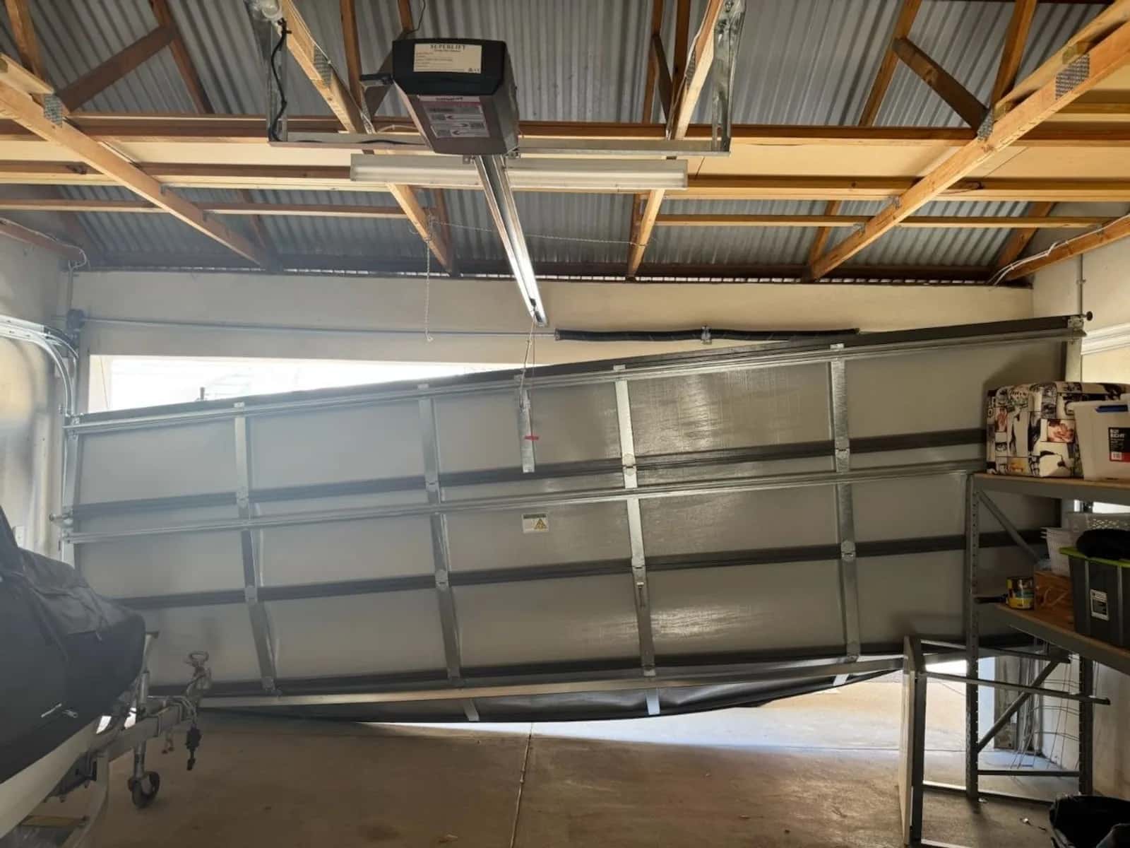 Rail-drive opener fixed to the ceiling above a sectional garage door, photographed from inside the garage
