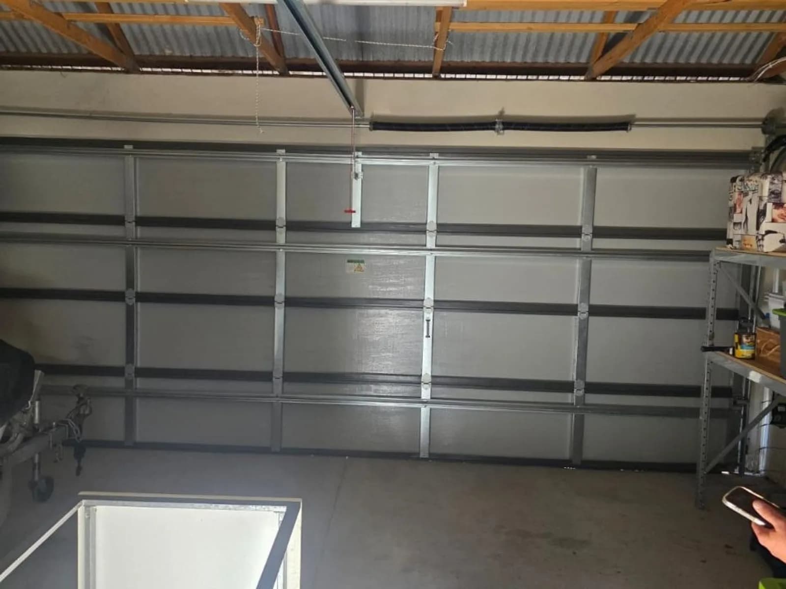 Garage door opener head unit fitted on its rail above a sectional door, the type of unit that carries the learn button near its light cover