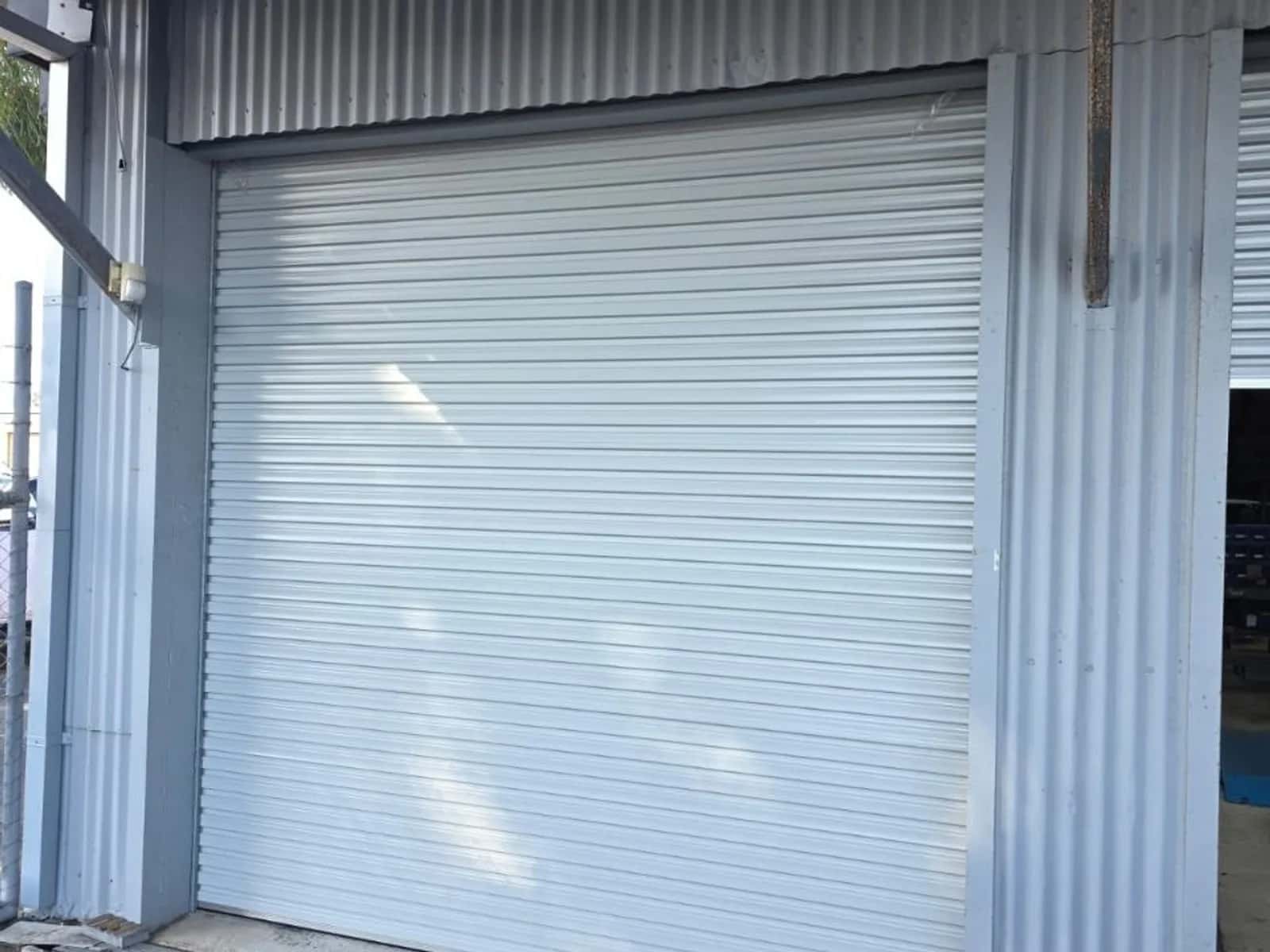 White industrial roller shutter closed across the full-height loading bay of a factory unit