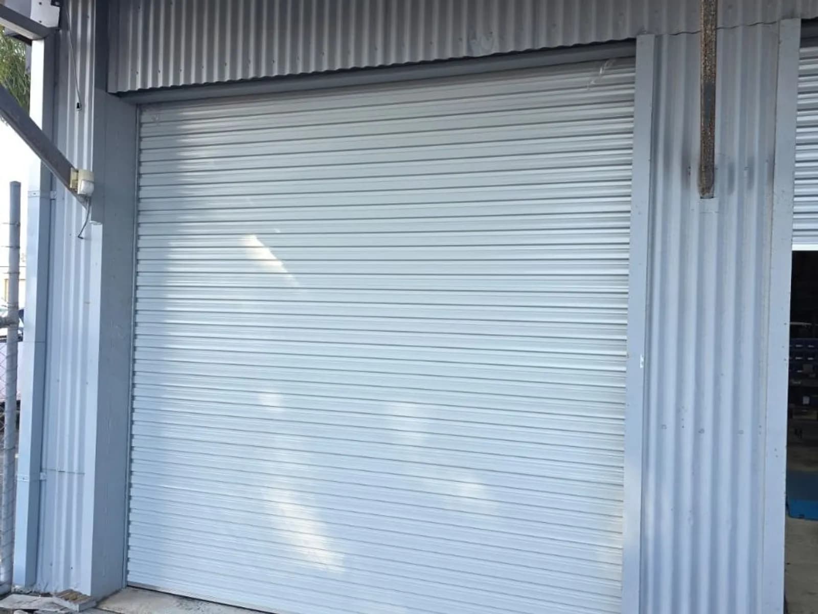 White industrial roller shutter closed across the full-height loading bay of a factory unit White industrial roller shutter closed across the full-height loading bay of a factory unit